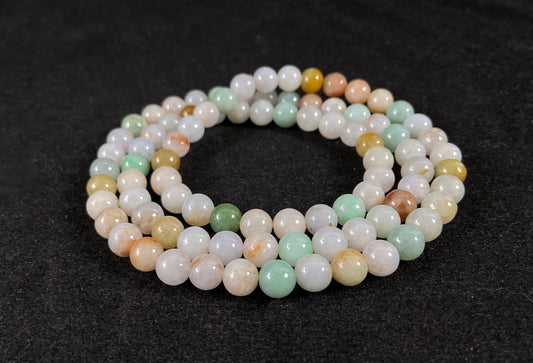 A jade bead strand featuring light green, tan, forest green, creamy white, and orange hues.