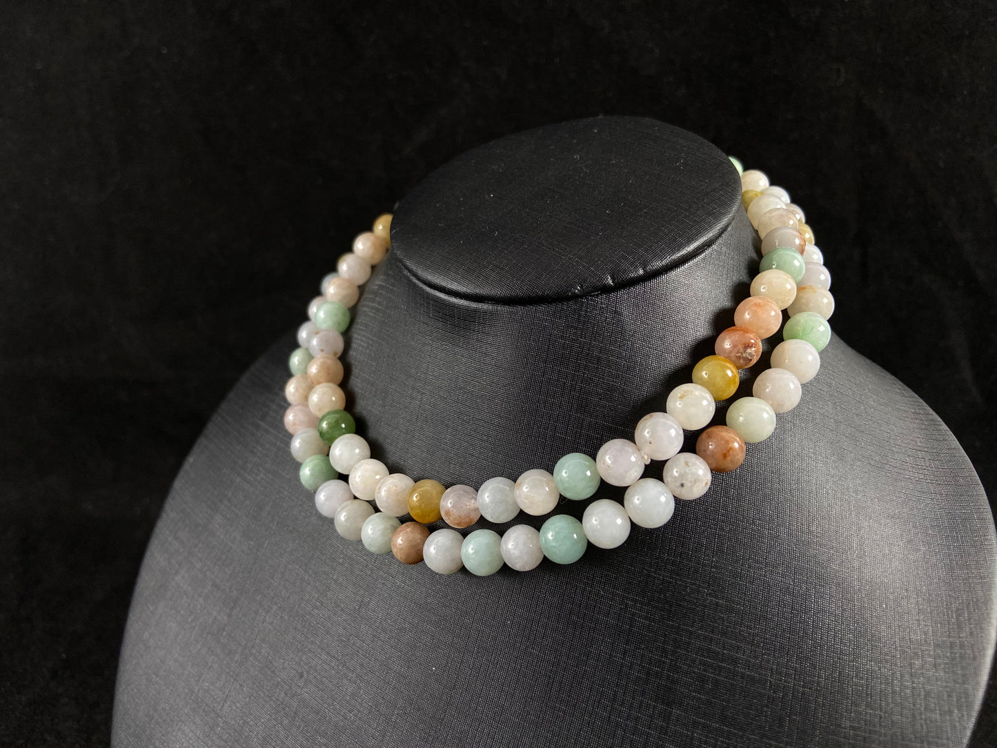 A jade bead strand featuring light green, tan, forest green, creamy white, and orange hues.