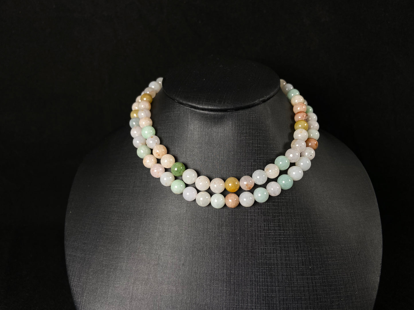 A jade bead strand featuring light green, tan, forest green, creamy white, and orange hues.