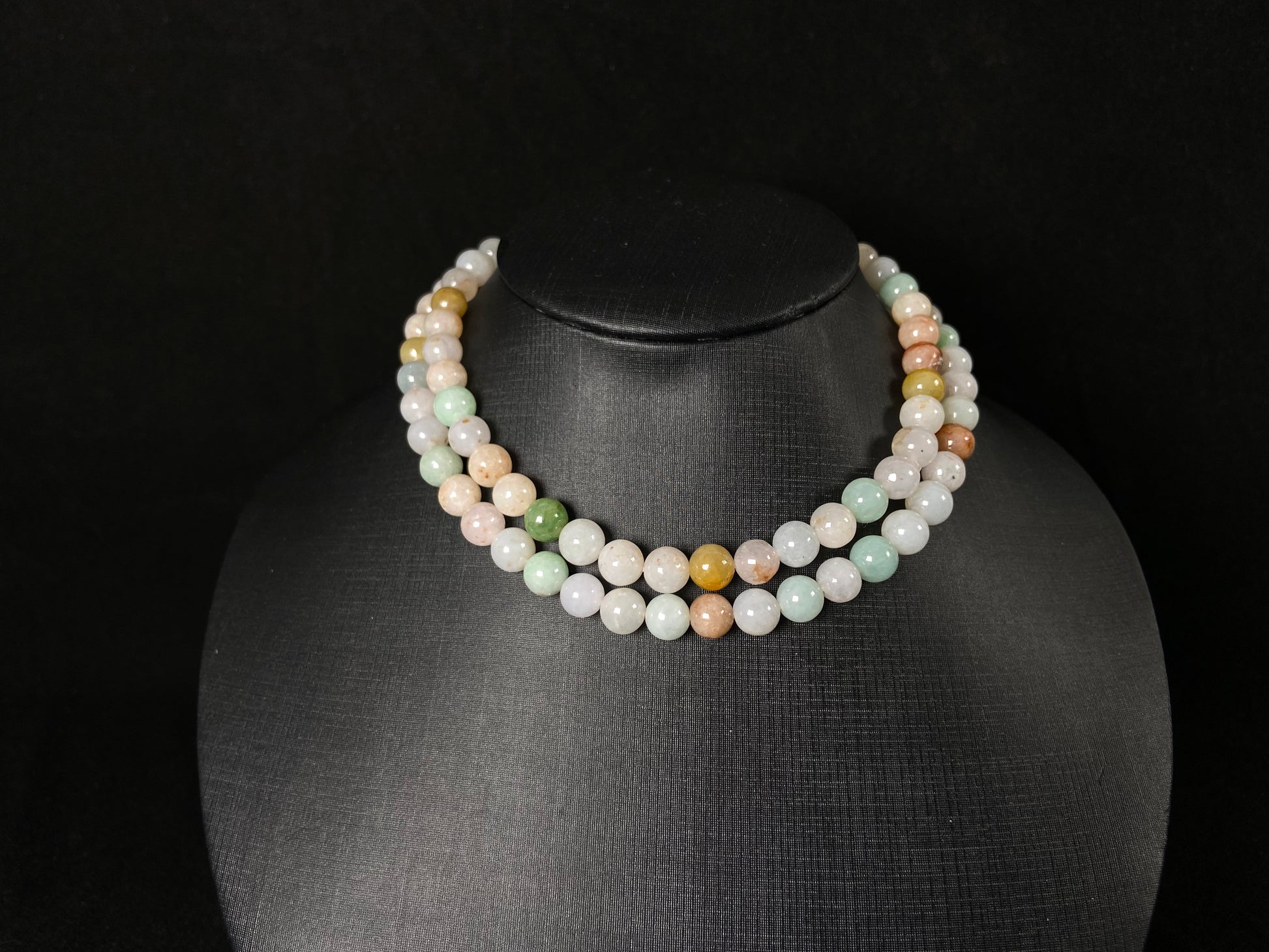 A jade bead strand featuring light green, tan, forest green, creamy white, and orange hues.