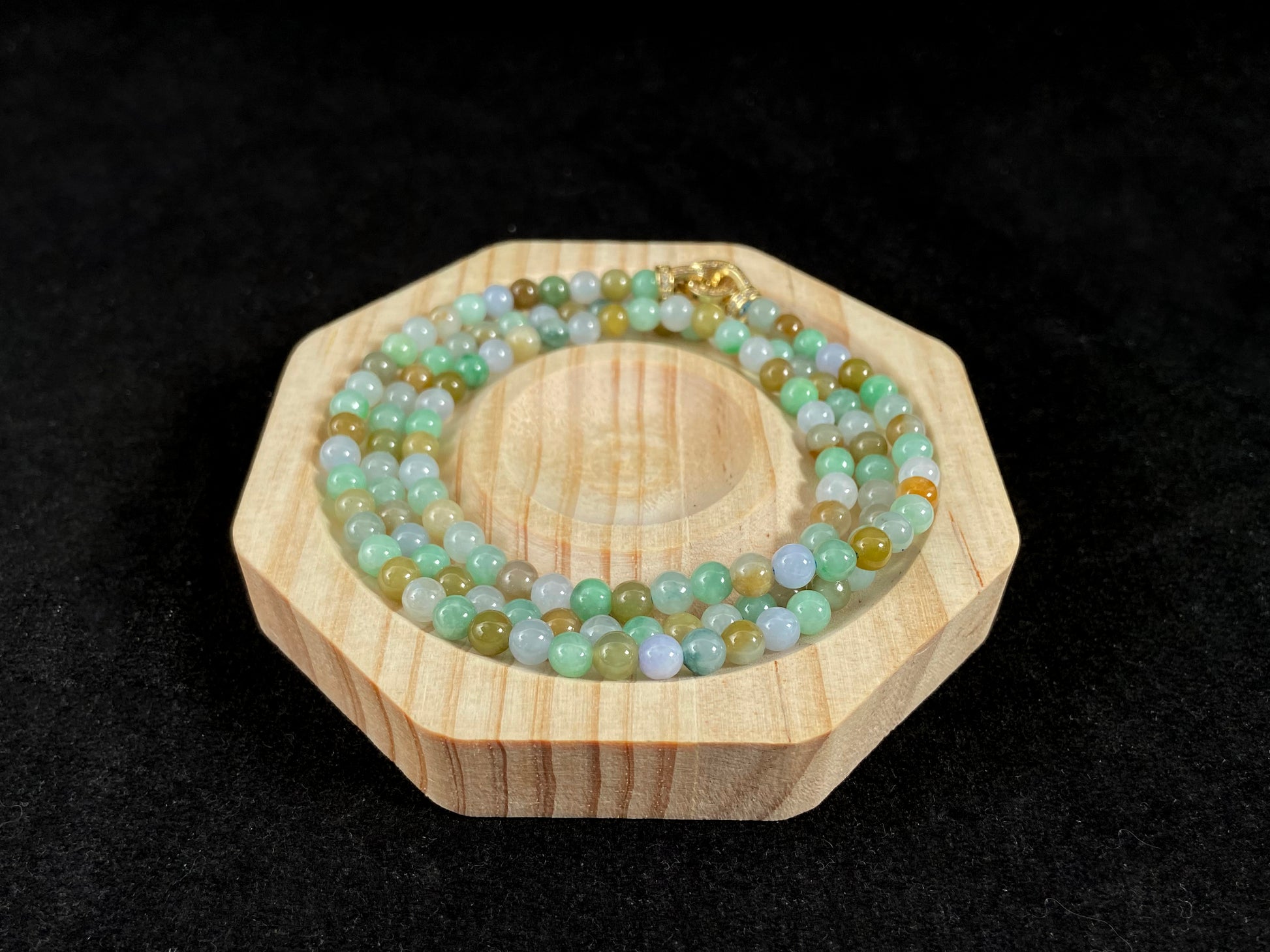 A jade bead strand featuring light green, creamy white and green beads