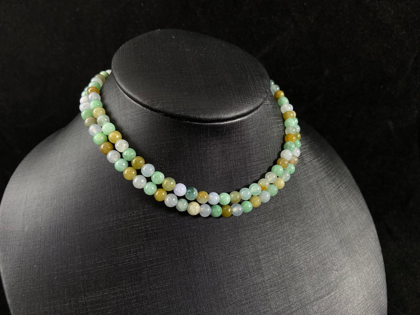 A jade bead strand featuring light green, creamy white and green beads