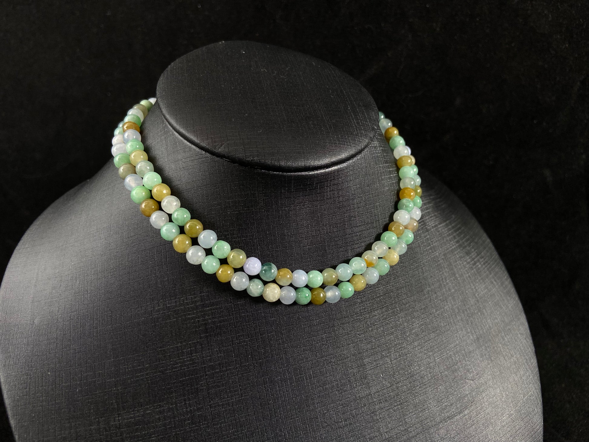 A jade bead strand featuring light green, creamy white and green beads