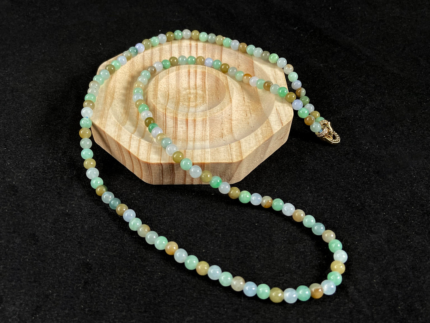 A jade bead strand featuring light green, creamy white and green beads