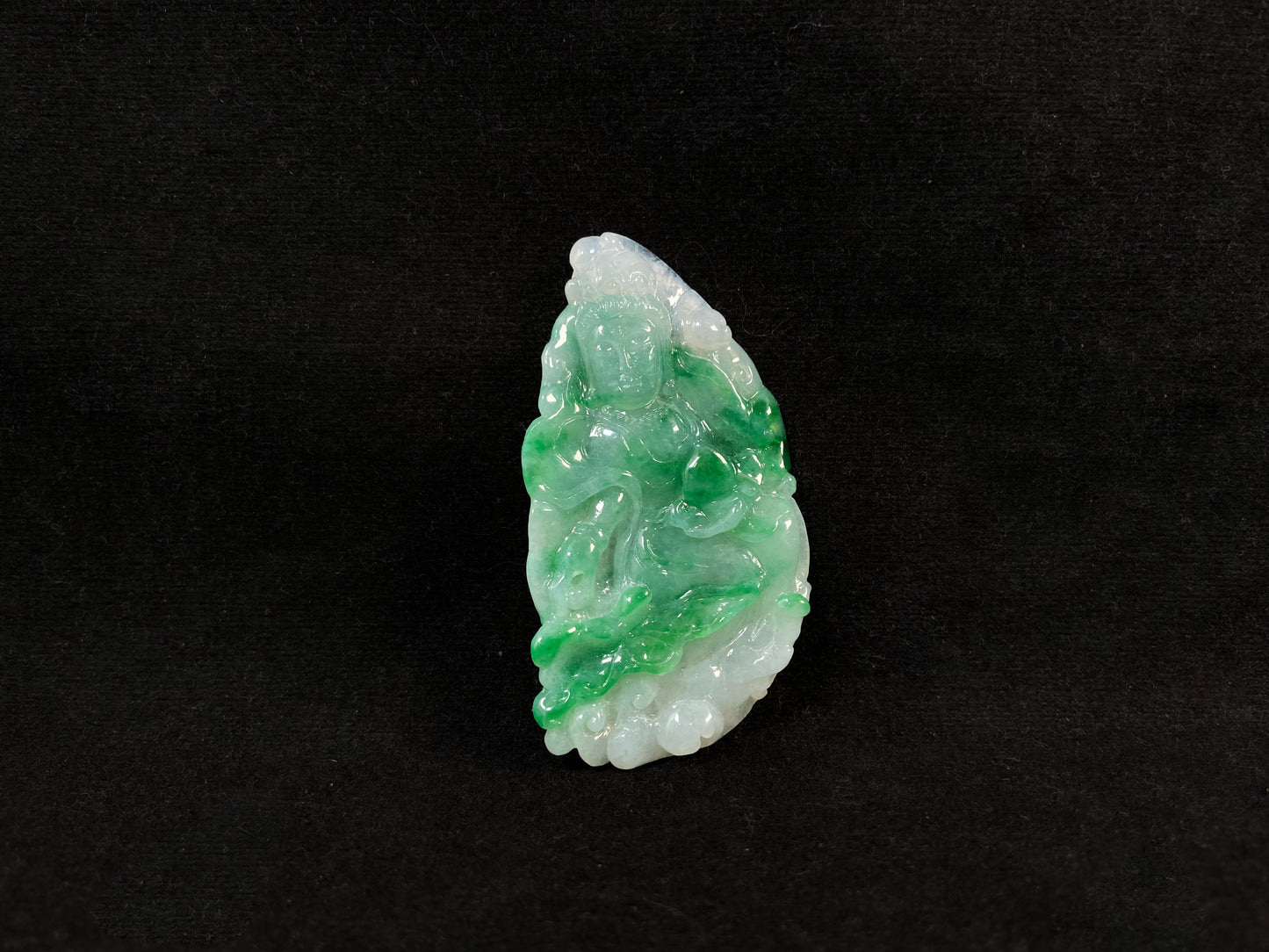 A Guanyin jade carving with a creamy white base and large green areas.