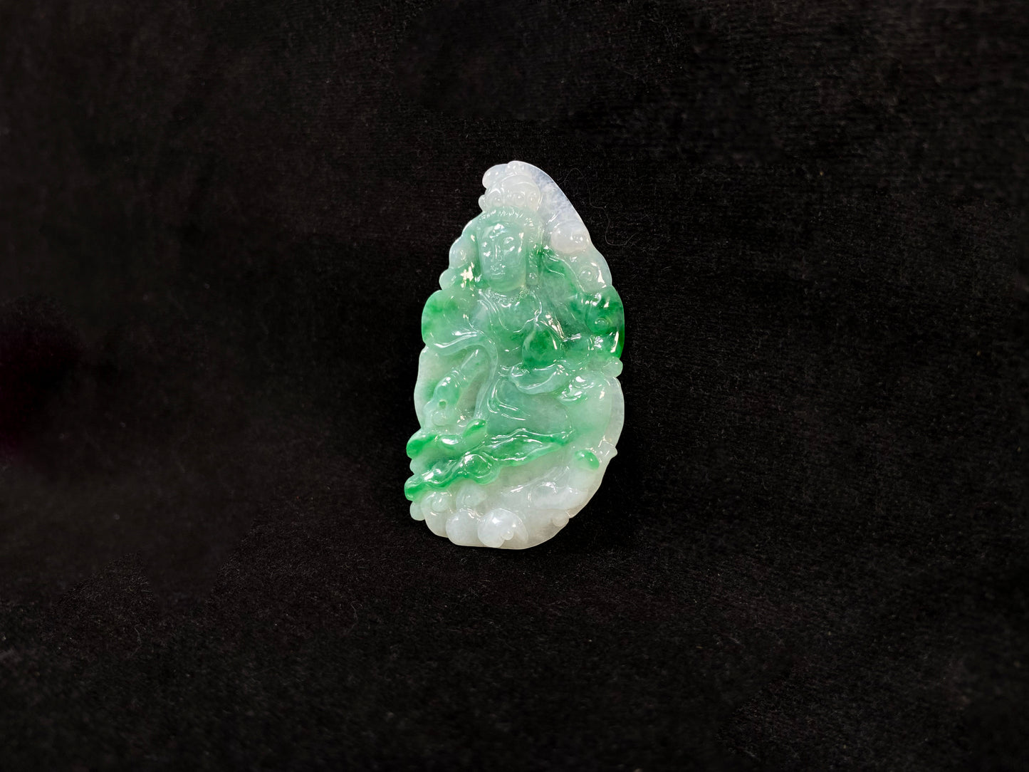 A Guanyin jade carving with a creamy white base and large green areas.