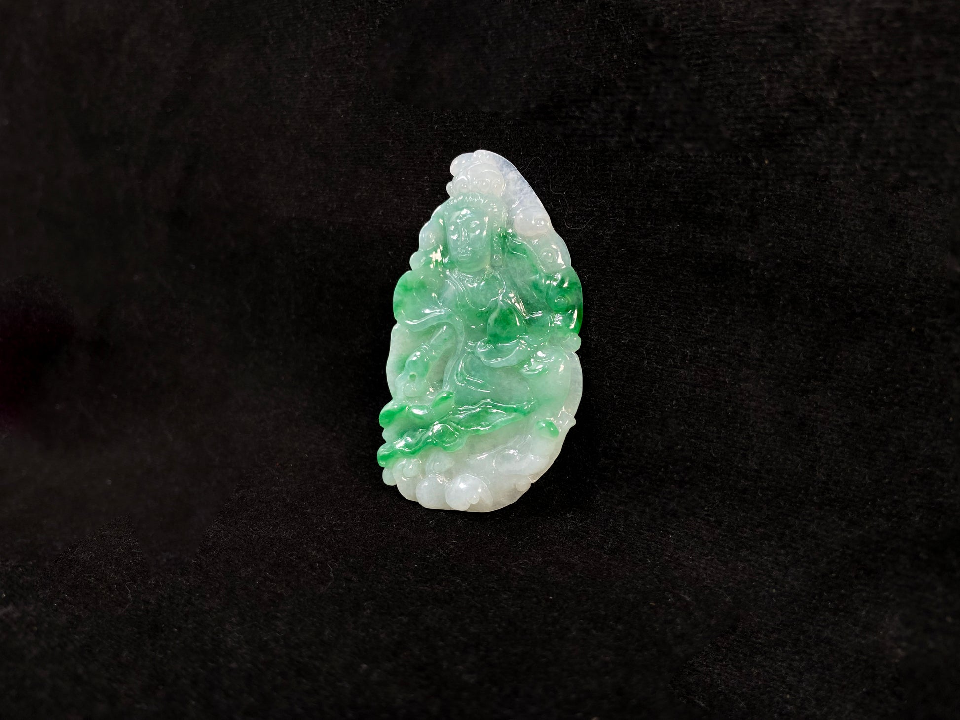 A Guanyin jade carving with a creamy white base and large green areas.