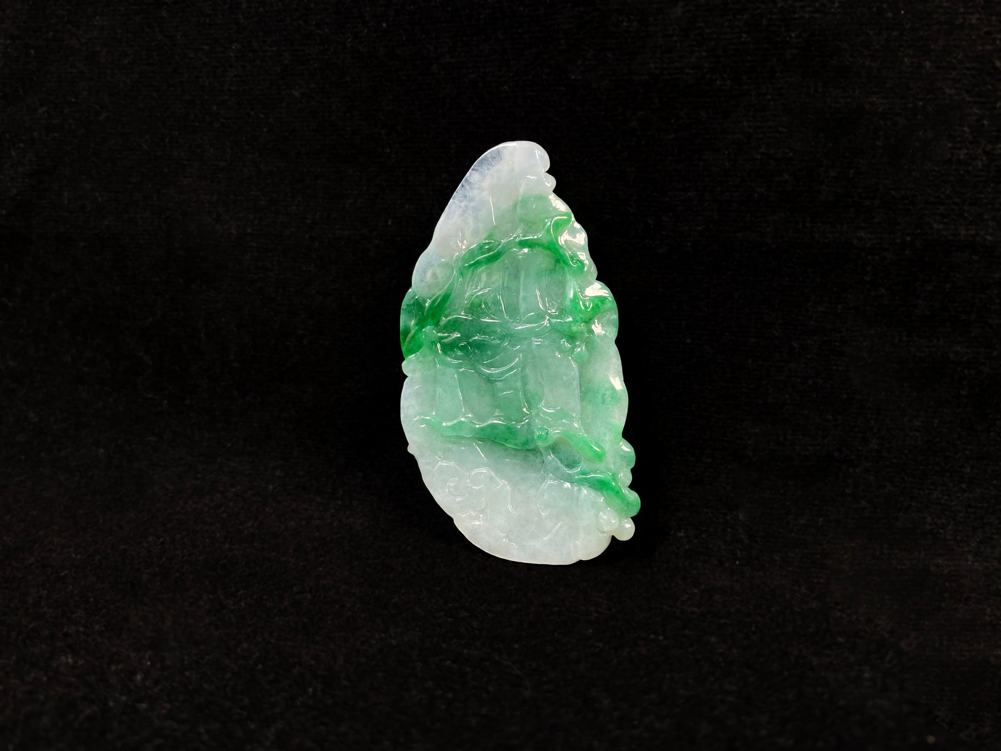 A Guanyin jade carving with a creamy white base and large green areas.