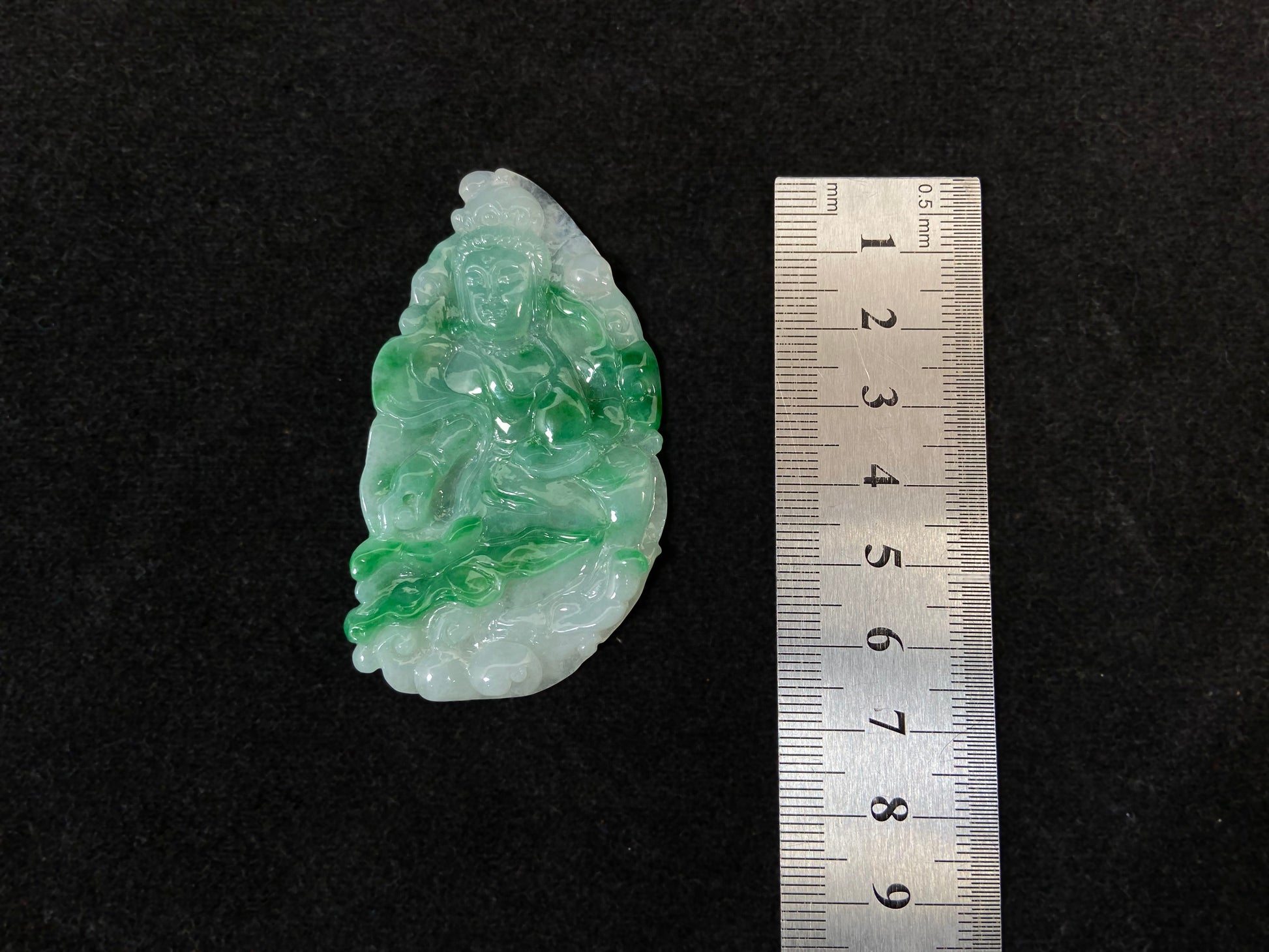 A Guanyin jade carving with a creamy white base and large green areas.