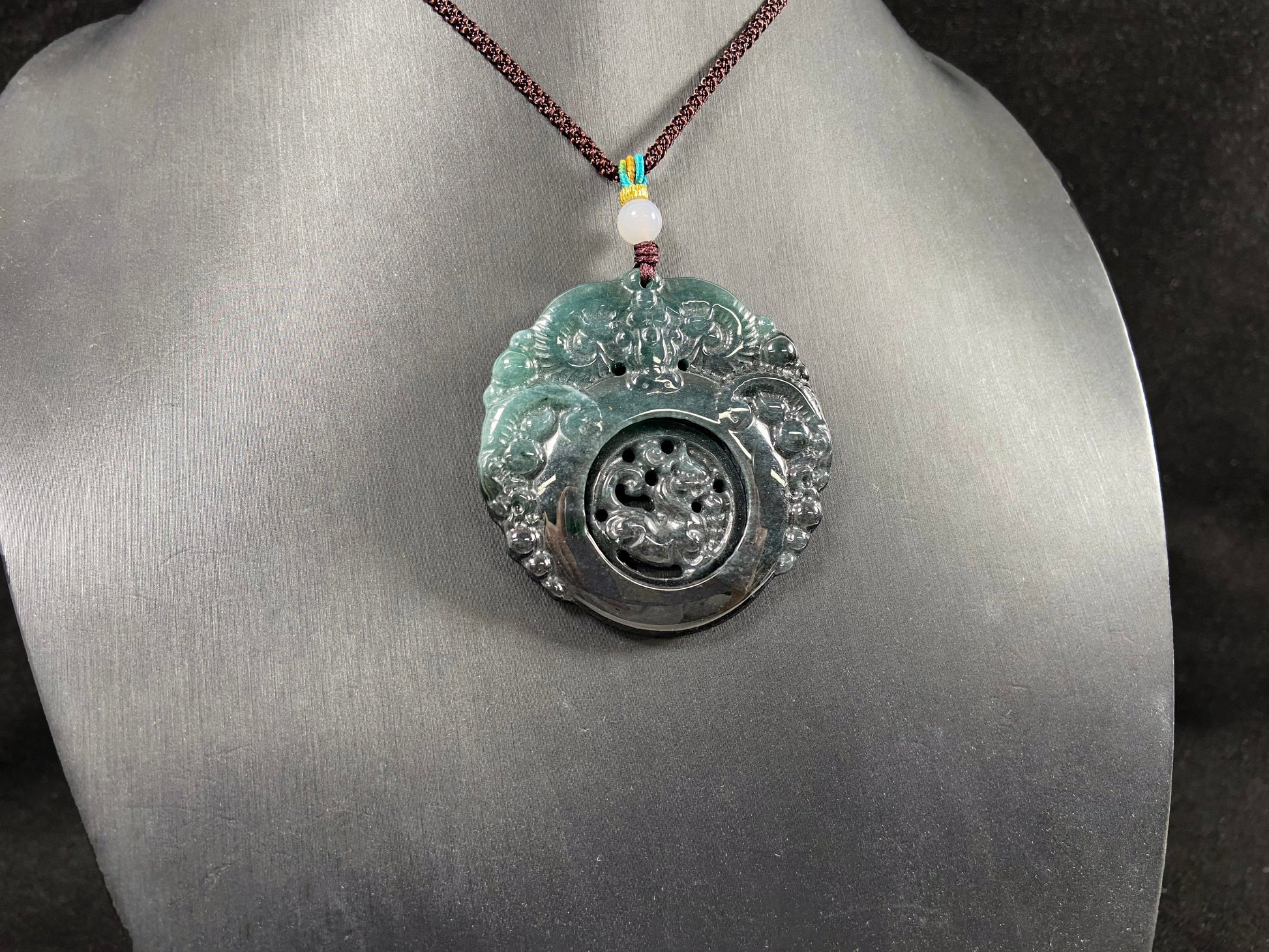 This jadeite pendant is a bi-color plaque, half deep green and half gray-black, carved with a kylin.