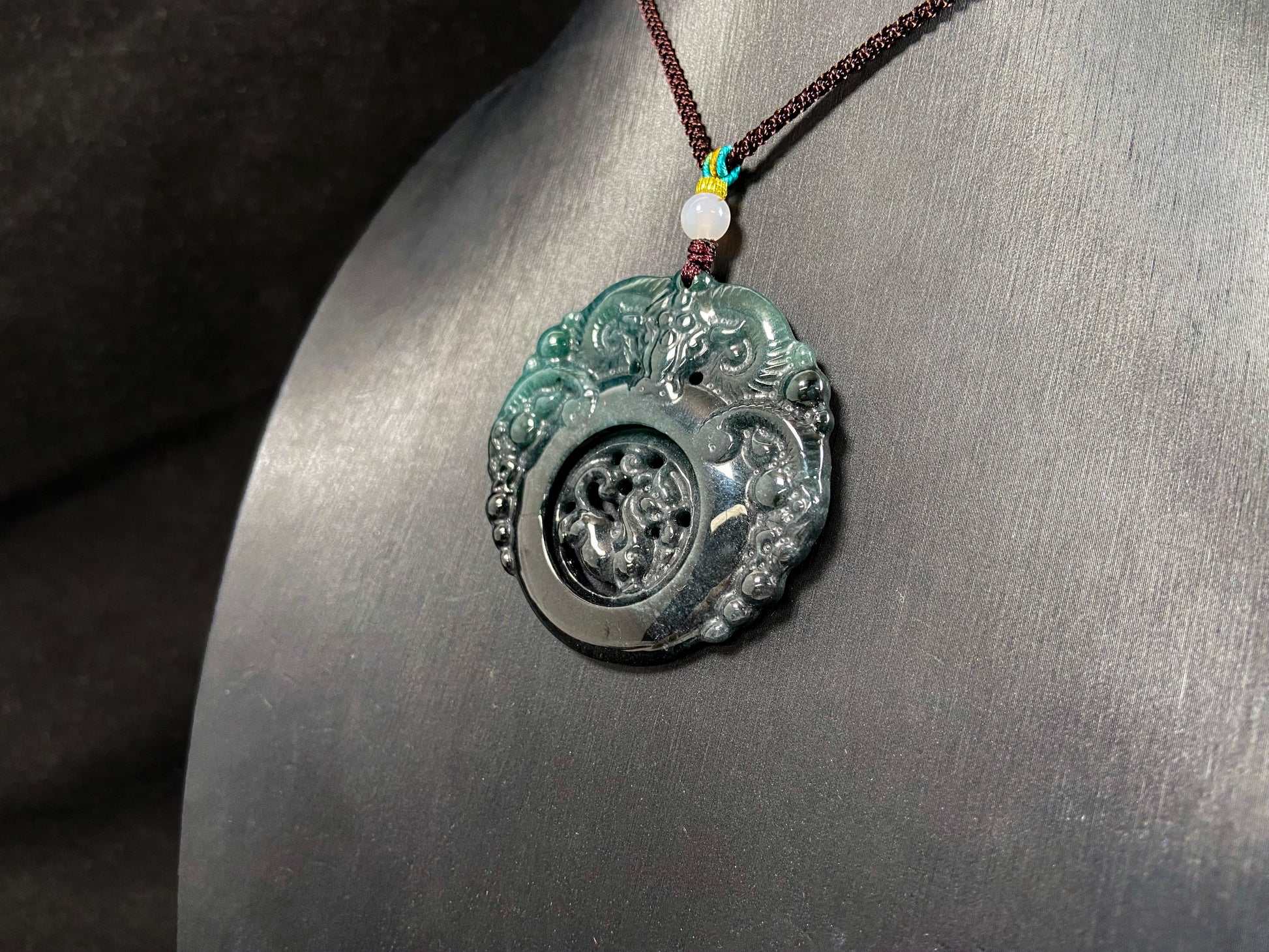 This jadeite pendant is a bi-color plaque, half deep green and half gray-black, carved with a kylin.