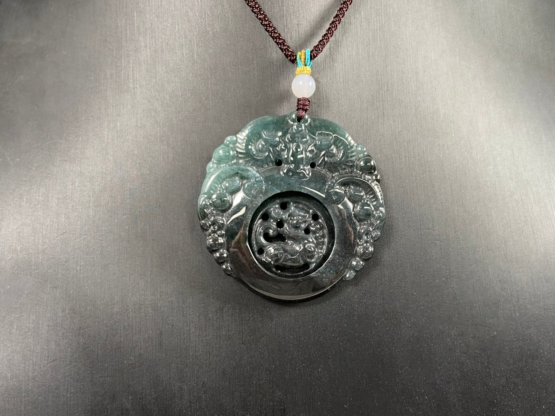 This jadeite pendant is a bi-color plaque, half deep green and half gray-black, carved with a kylin.