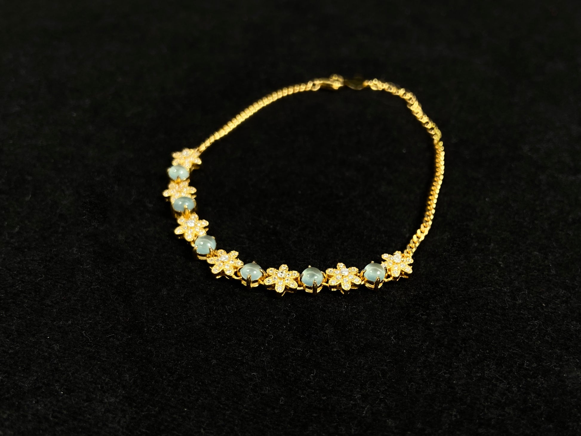 This bracelet features icy jadeite cabochons and diamond-covered gold flowers, alternately set in gold-plated 925 silver.