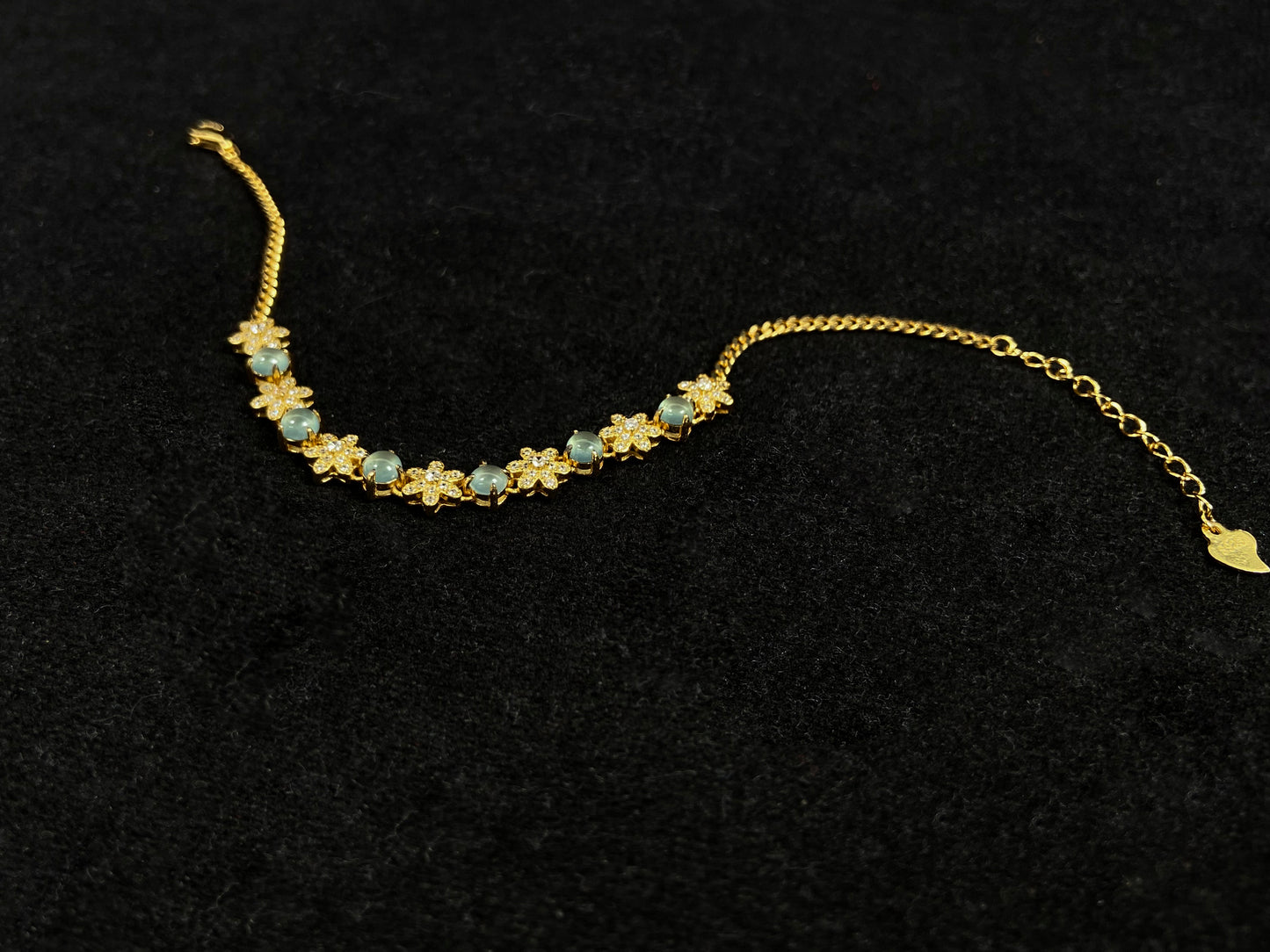 This bracelet features icy jadeite cabochons and diamond-covered gold flowers, alternately set in gold-plated 925 silver.