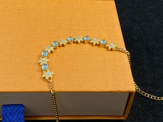 This bracelet features icy jadeite cabochons and diamond-covered gold flowers, alternately set in gold-plated 925 silver.