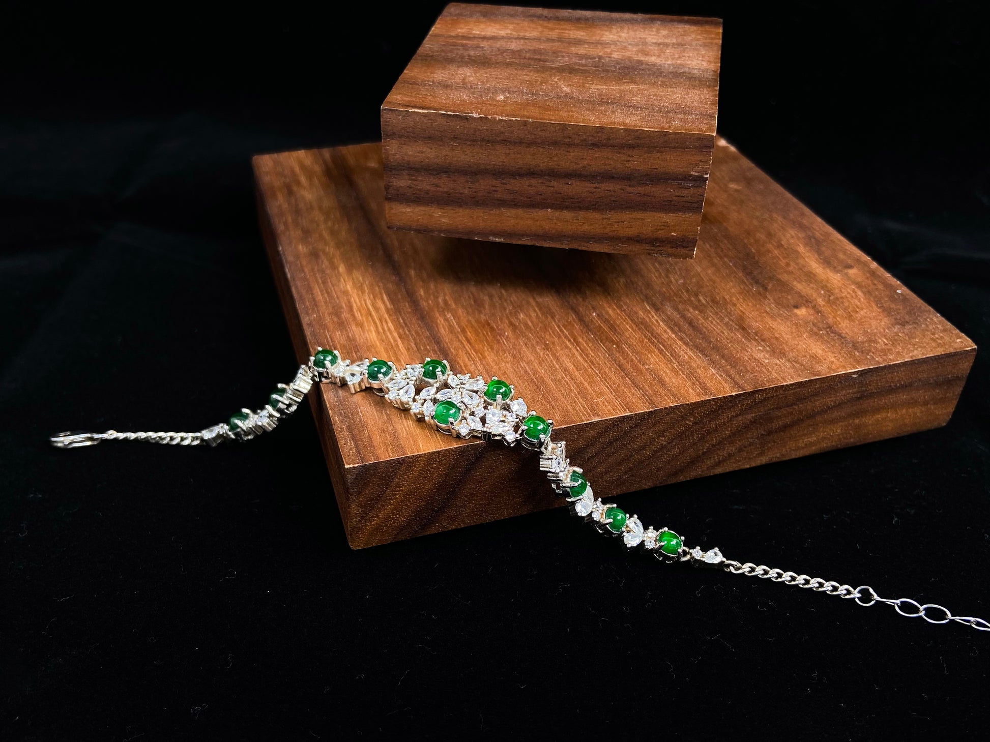 This elegant bracelet features green jade cabochons claw-set in 925 silver, with petal-shaped settings adorned with diamonds.