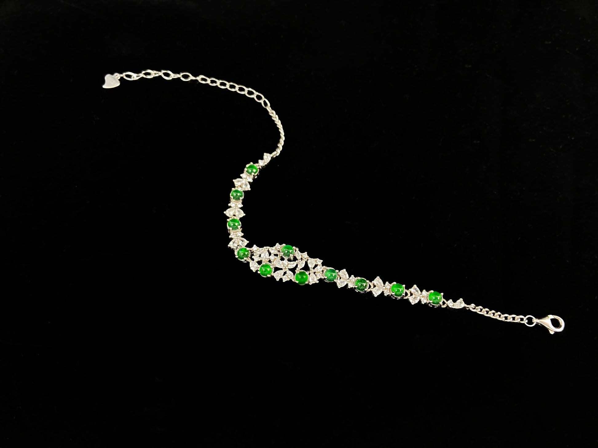 This elegant bracelet features green jade cabochons claw-set in 925 silver, with petal-shaped settings adorned with diamonds.