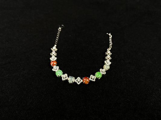 A jadeite bracelet with brown, green, and icy cabochons, each separated by sterling silver flowers set with diamond centers.