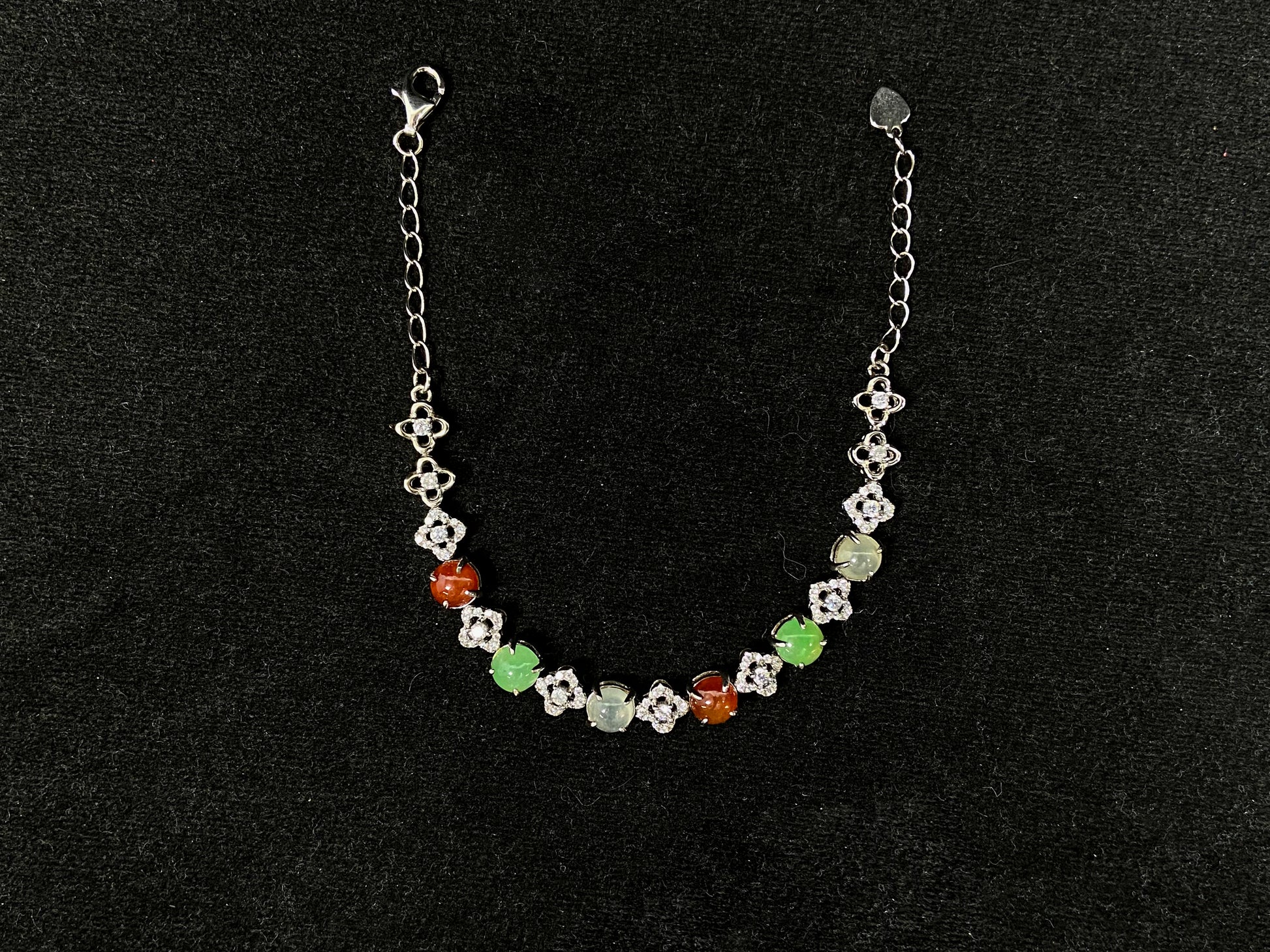 A jadeite bracelet with brown, green, and icy cabochons, each separated by sterling silver flowers set with diamond centers.