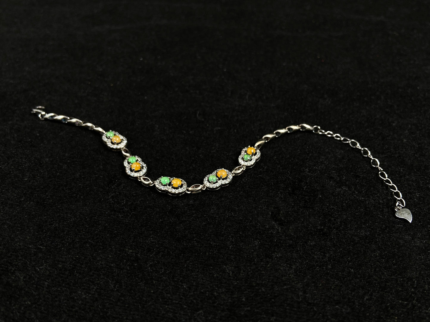 A hollow gourd-shaped bracelet in 925 silver, set with a large yellow cabochon and small apple-green cabochon, accented with diamonds.