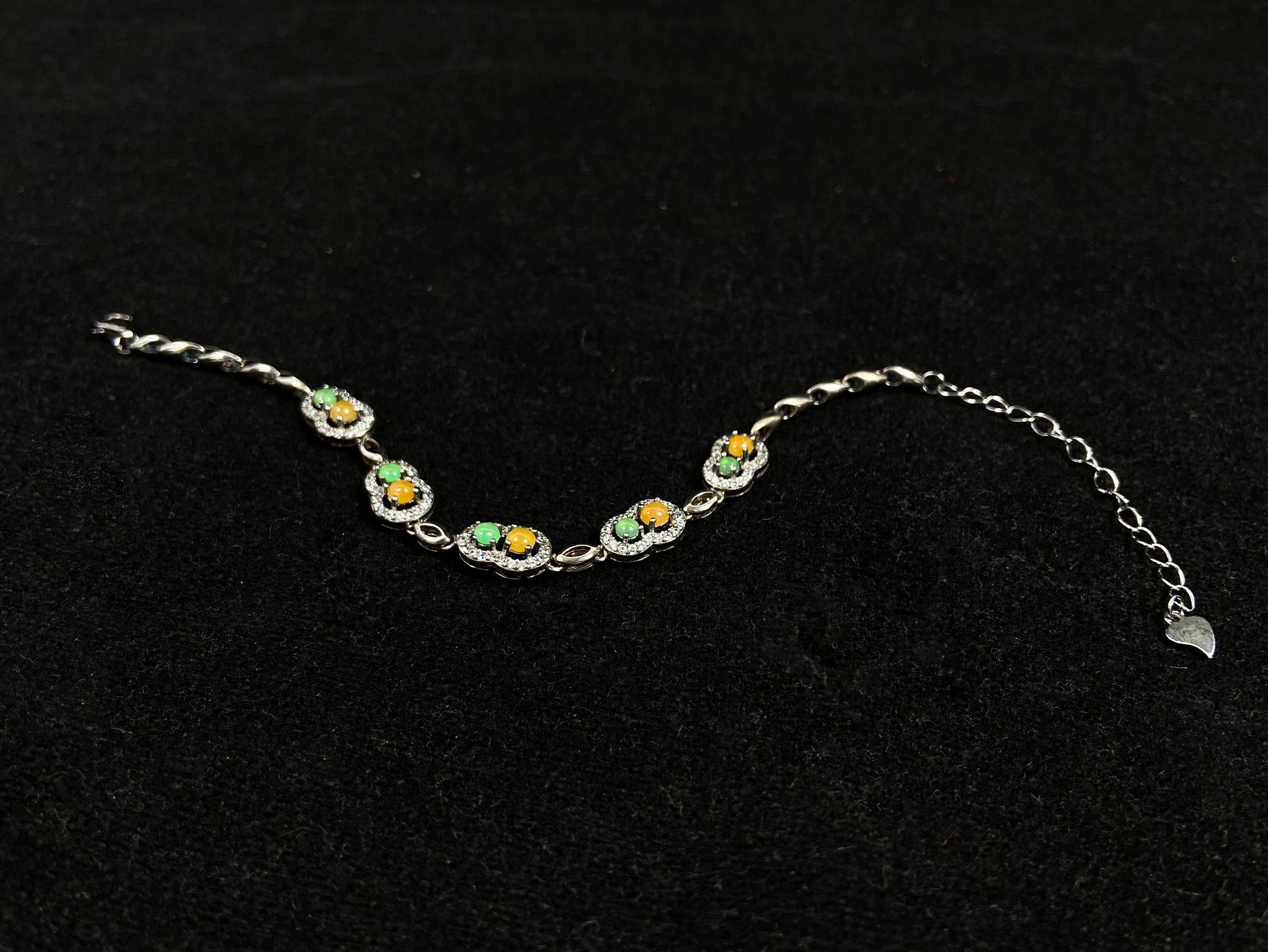 A hollow gourd-shaped bracelet in 925 silver, set with a large yellow cabochon and small apple-green cabochon, accented with diamonds.