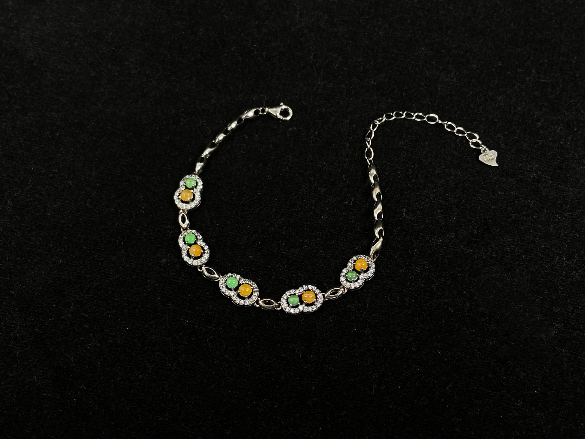 A hollow gourd-shaped bracelet in 925 silver, set with a large yellow cabochon and small apple-green cabochon, accented with diamonds.