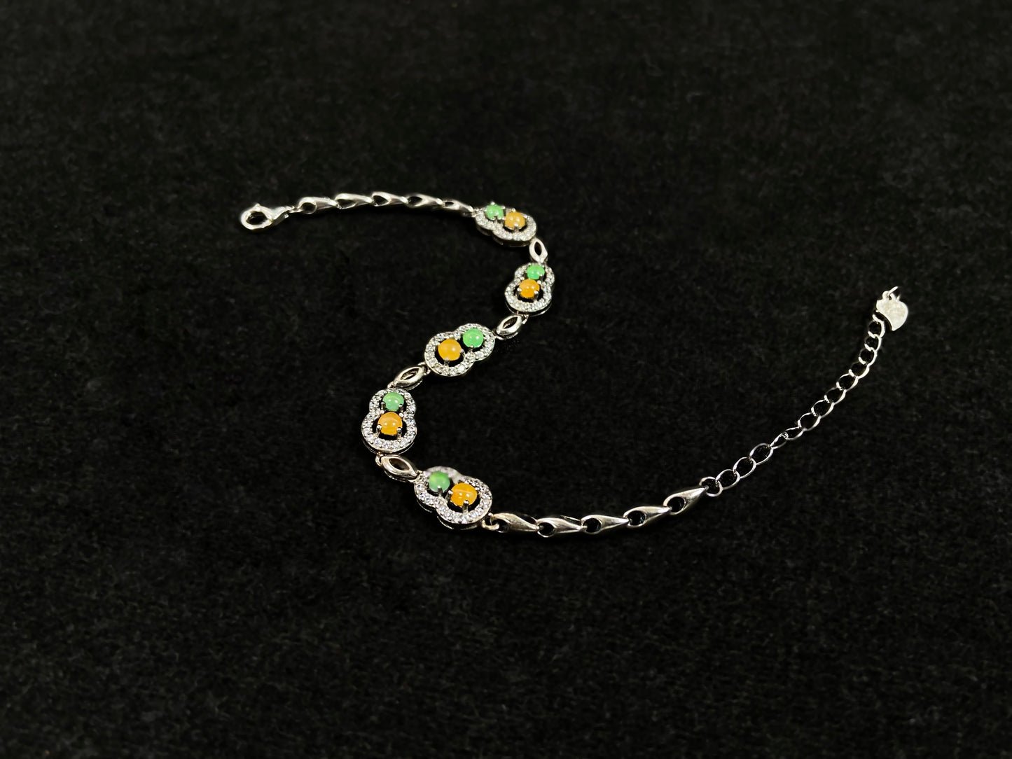 A hollow gourd-shaped bracelet in 925 silver, set with a large yellow cabochon and small apple-green cabochon, accented with diamonds.