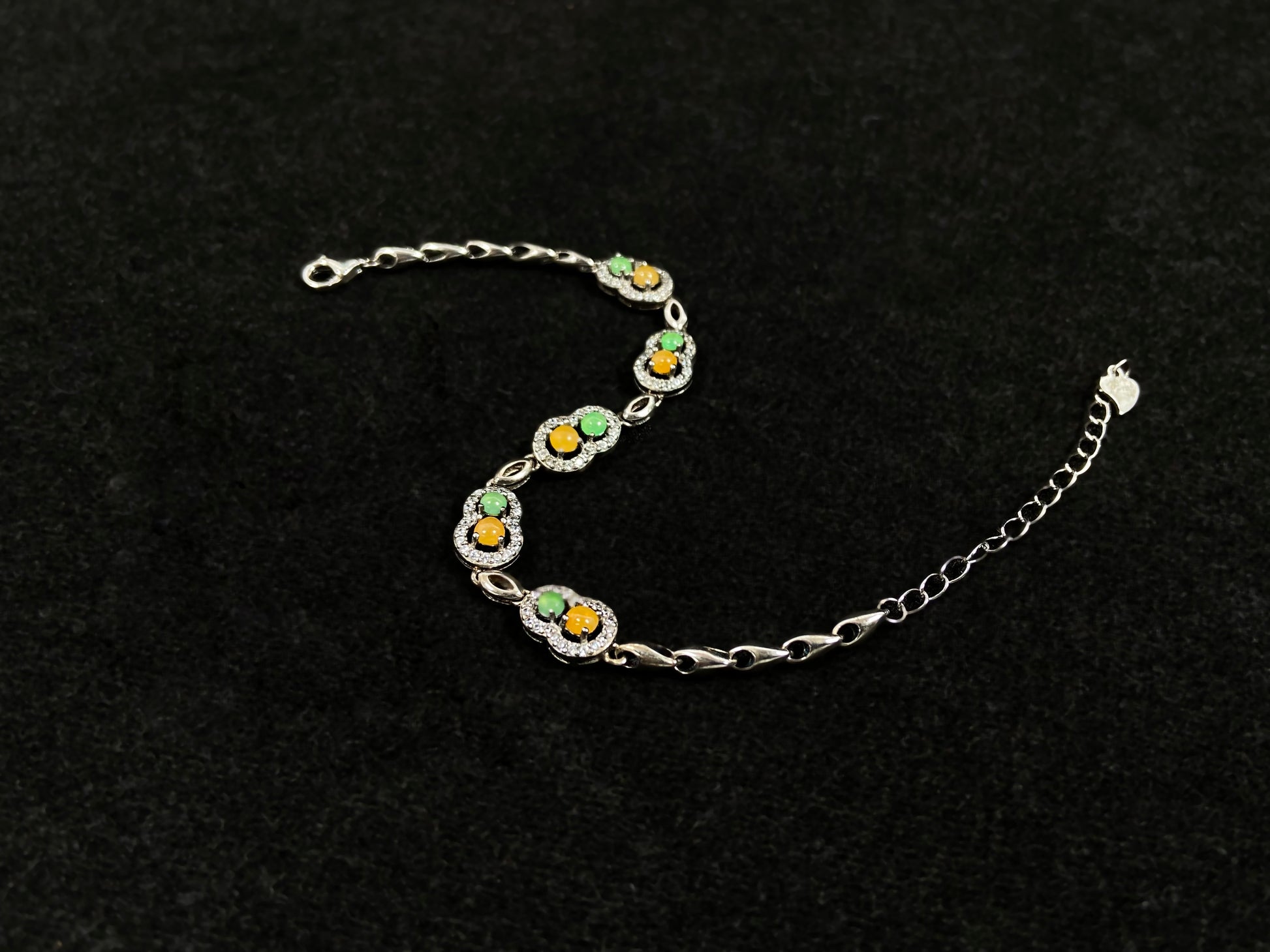 A hollow gourd-shaped bracelet in 925 silver, set with a large yellow cabochon and small apple-green cabochon, accented with diamonds.