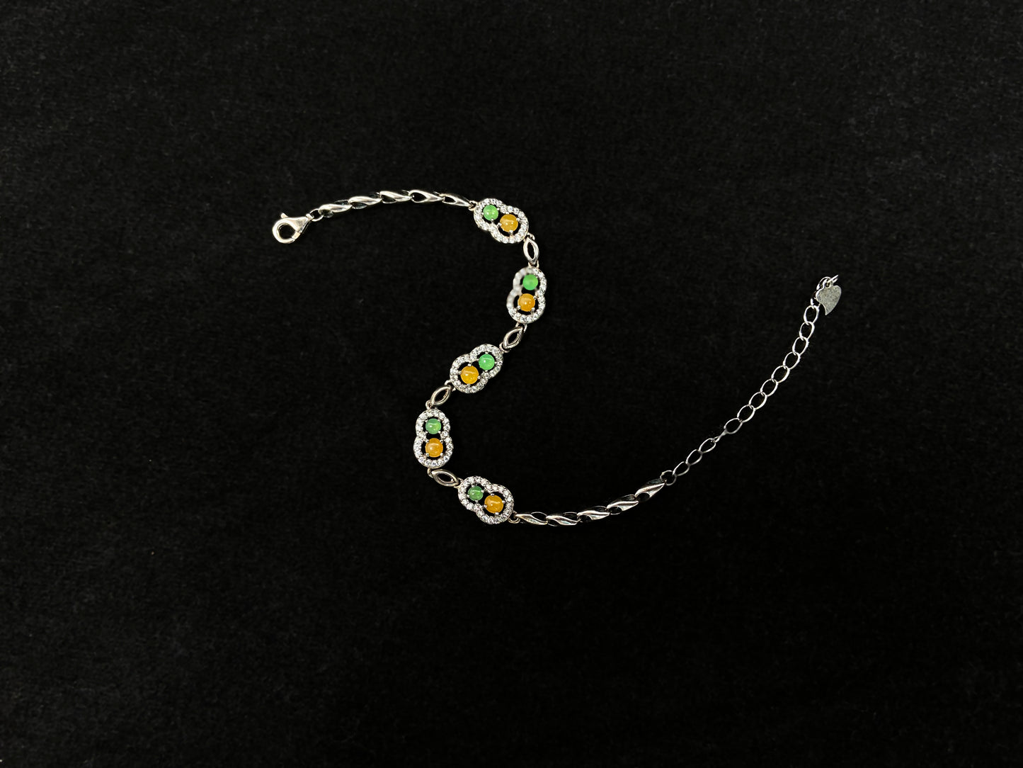 A hollow gourd-shaped bracelet in 925 silver, set with a large yellow cabochon and small apple-green cabochon, accented with diamonds.