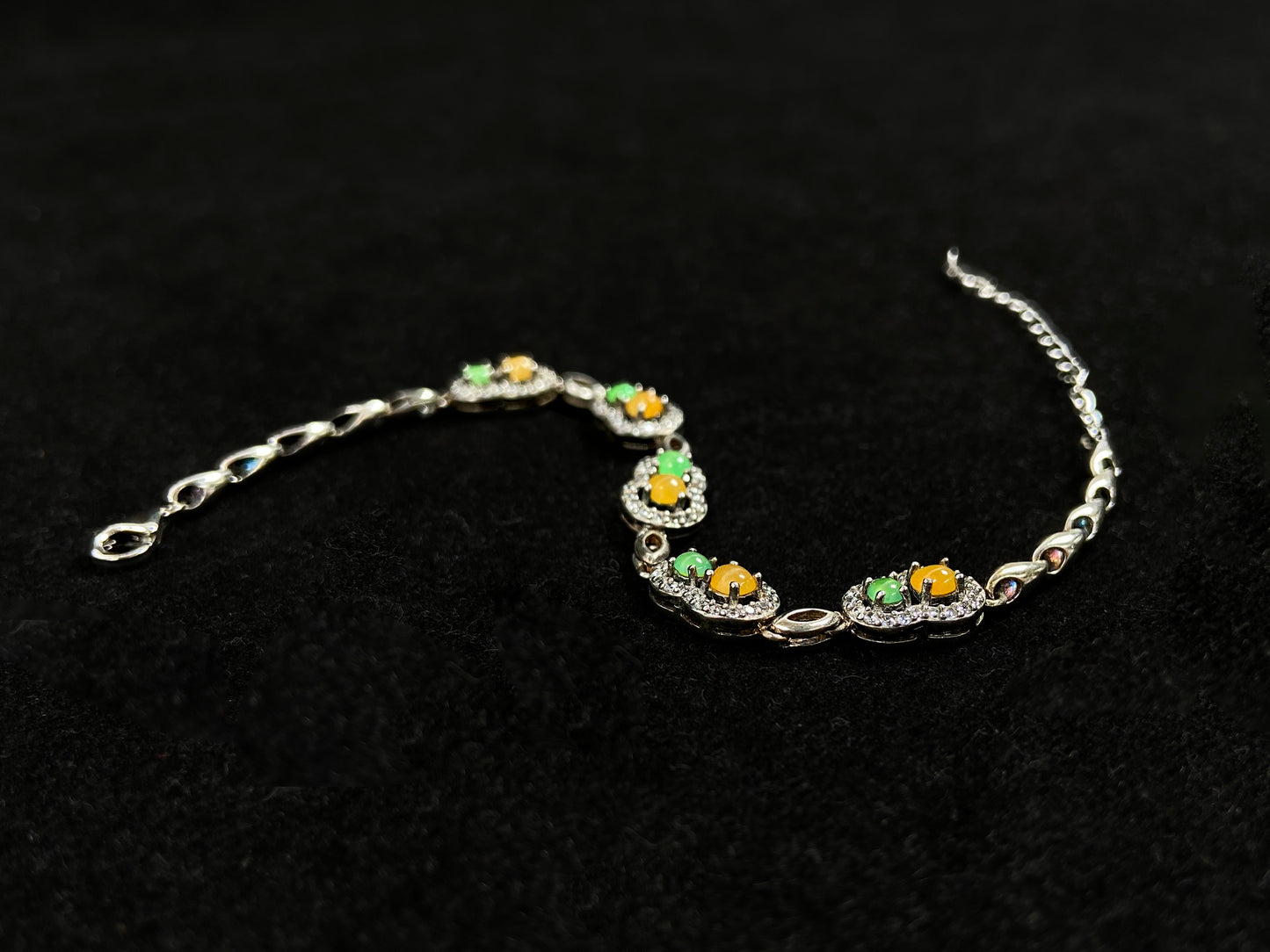 A hollow gourd-shaped bracelet in 925 silver, set with a large yellow cabochon and small apple-green cabochon, accented with diamonds.