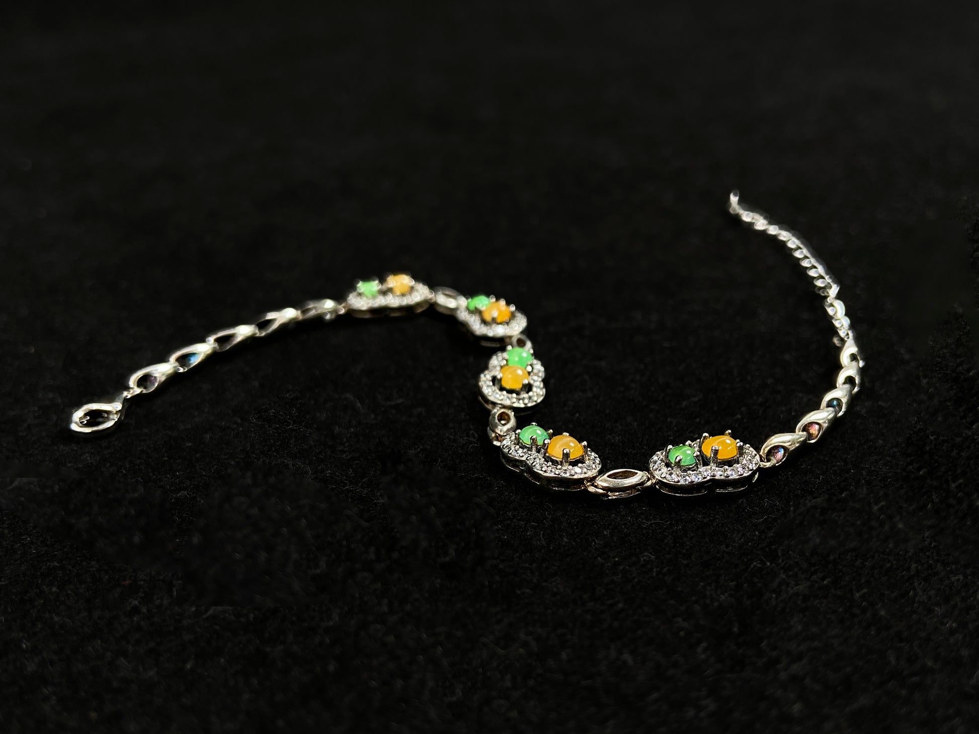 A hollow gourd-shaped bracelet in 925 silver, set with a large yellow cabochon and small apple-green cabochon, accented with diamonds.