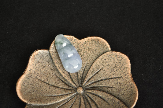 Decorative item with a green stone on a textured surface