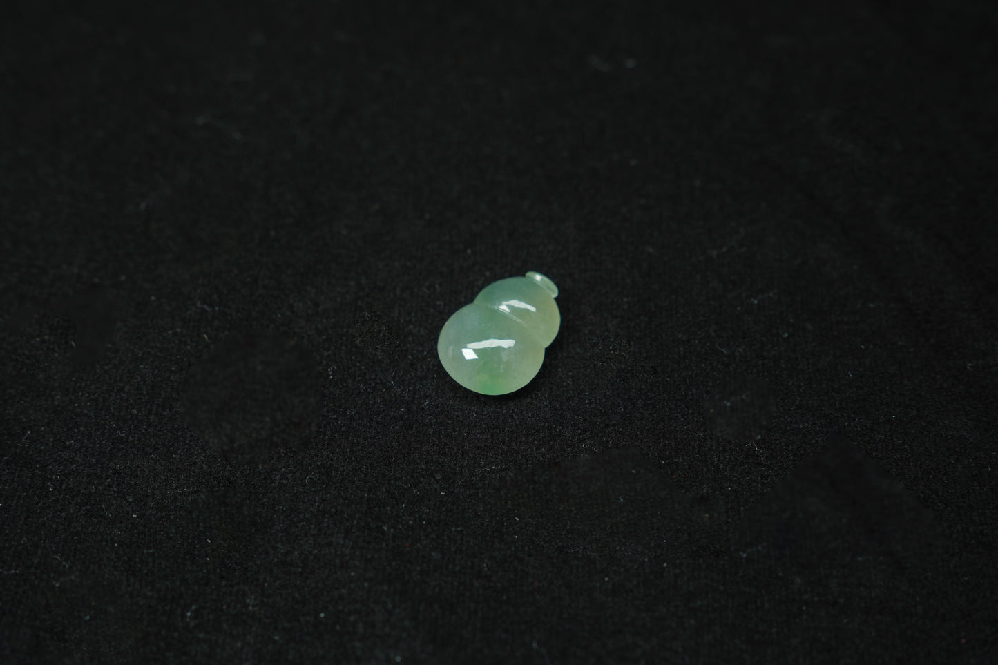 A pale green translucent jade gourd, expertly carved and polished.