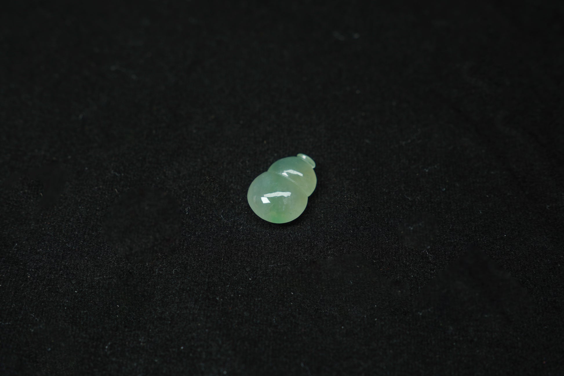 A pale green translucent jade gourd, expertly carved and polished.