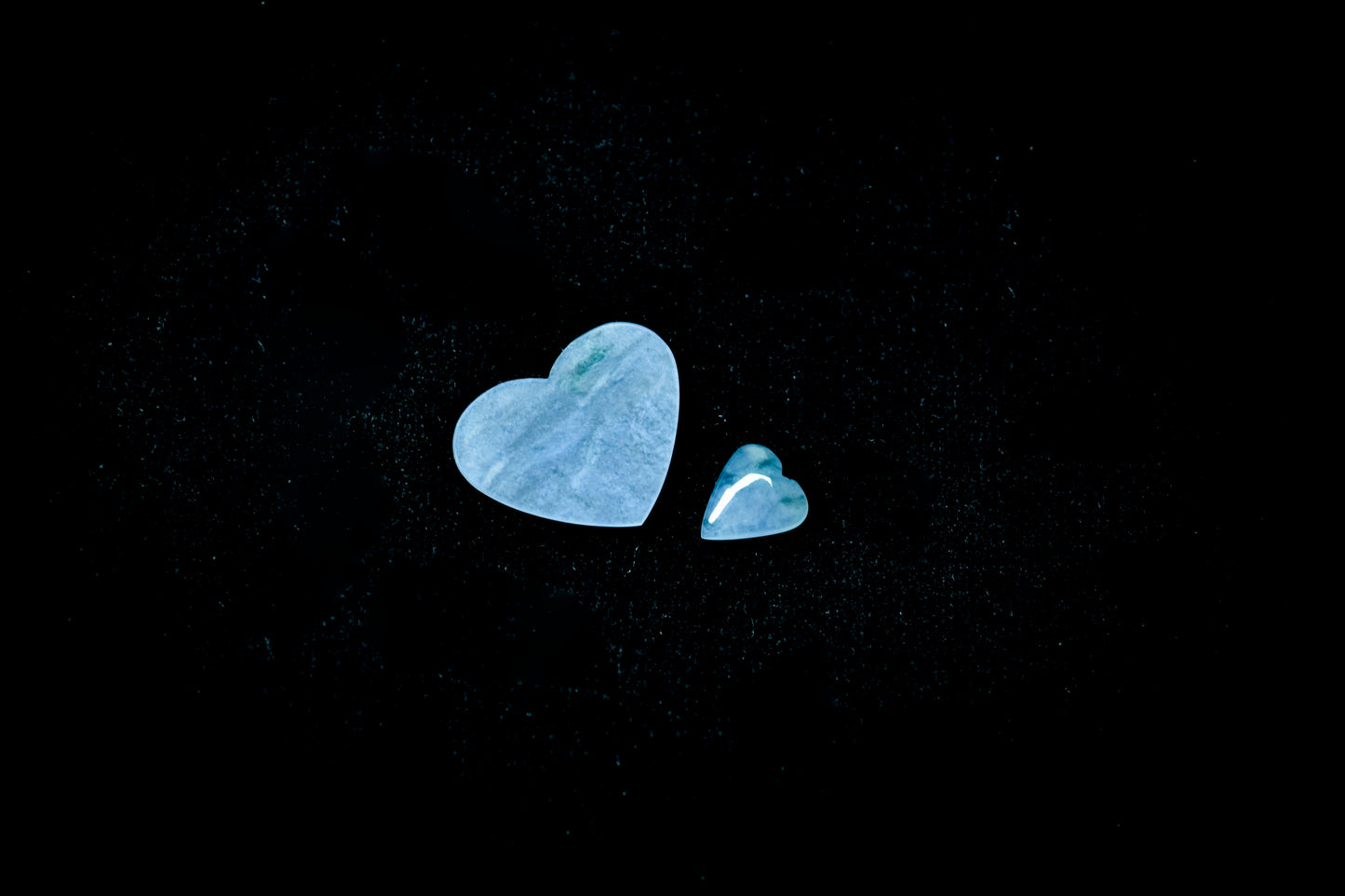 A heart shaped jade stone in a soft blue hue with wispy inclusions.