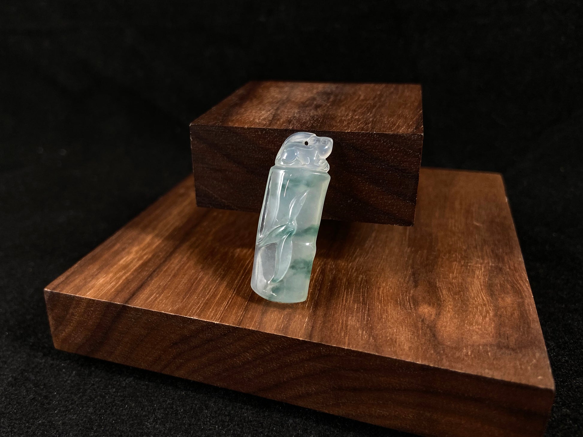 A translucent bamboo shaped jade pendant with floating green accents, symbolizing continual growth and career success.