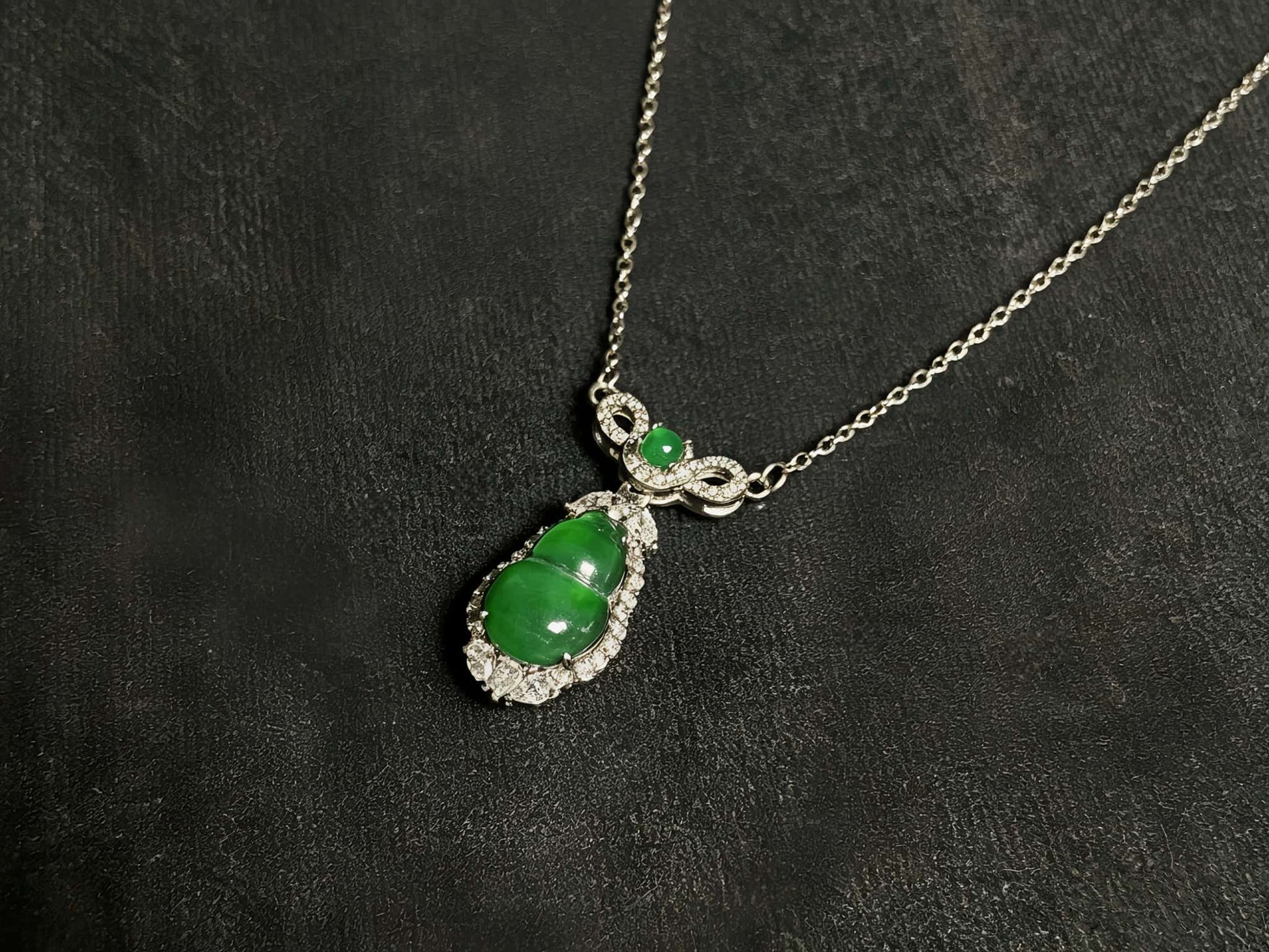 A glossy green lucky gourd jadeite pendant.