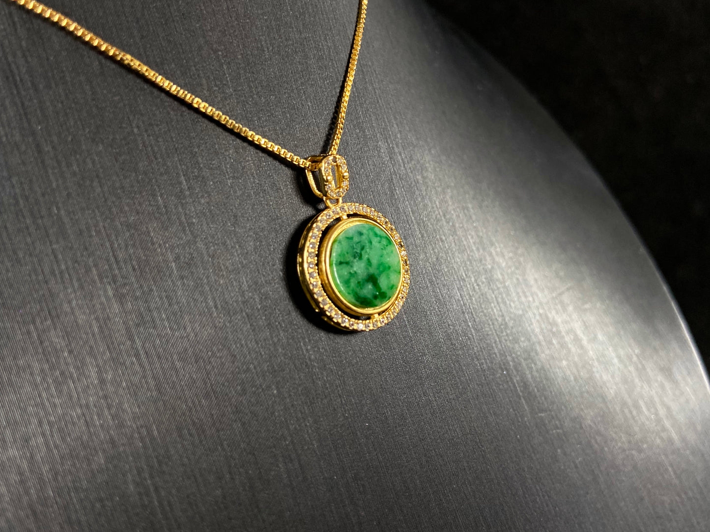 This pendant centers a small, round jadeite with a translucent white base and wisps of green, framed by a wide band of 925 silver.