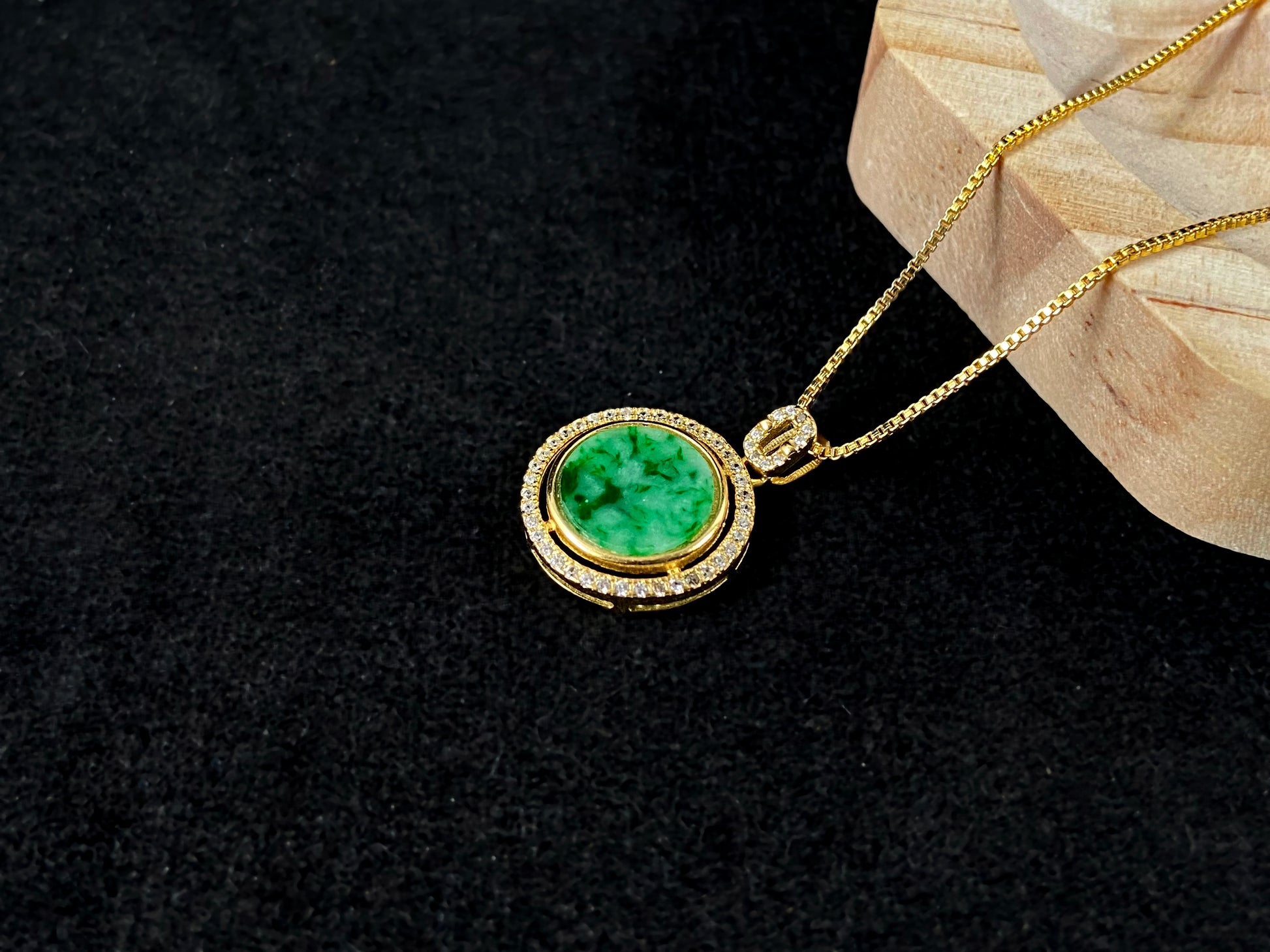 This pendant centers a small, round jadeite with a translucent white base and wisps of green, framed by a wide band of 925 silver.