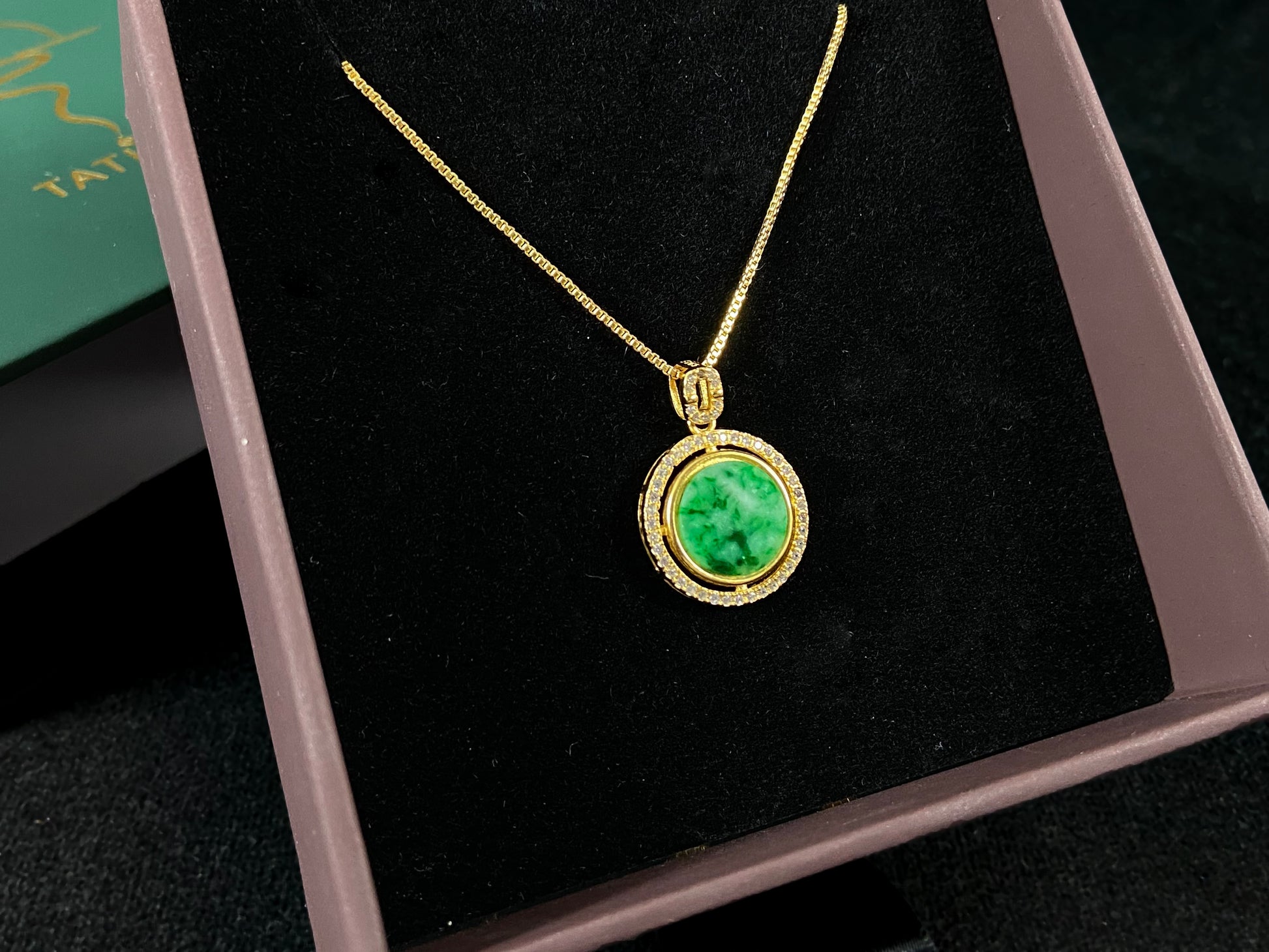 This pendant centers a small, round jadeite with a translucent white base and wisps of green, framed by a wide band of 925 silver.