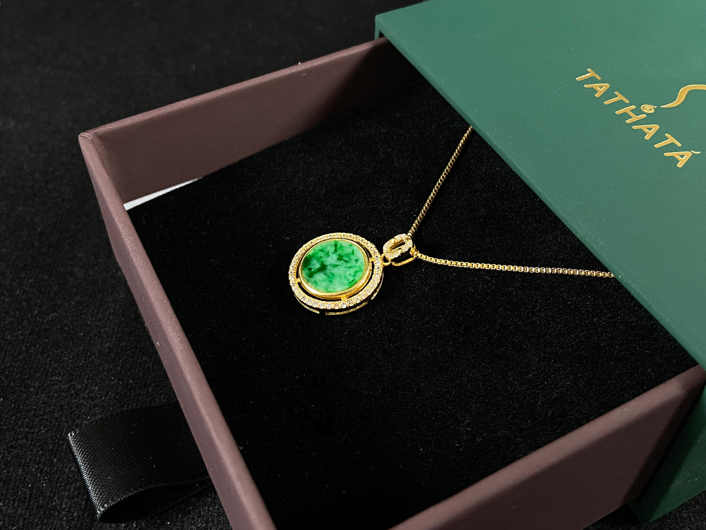 This pendant centers a small, round jadeite with a translucent white base and wisps of green, framed by a wide band of 925 silver.