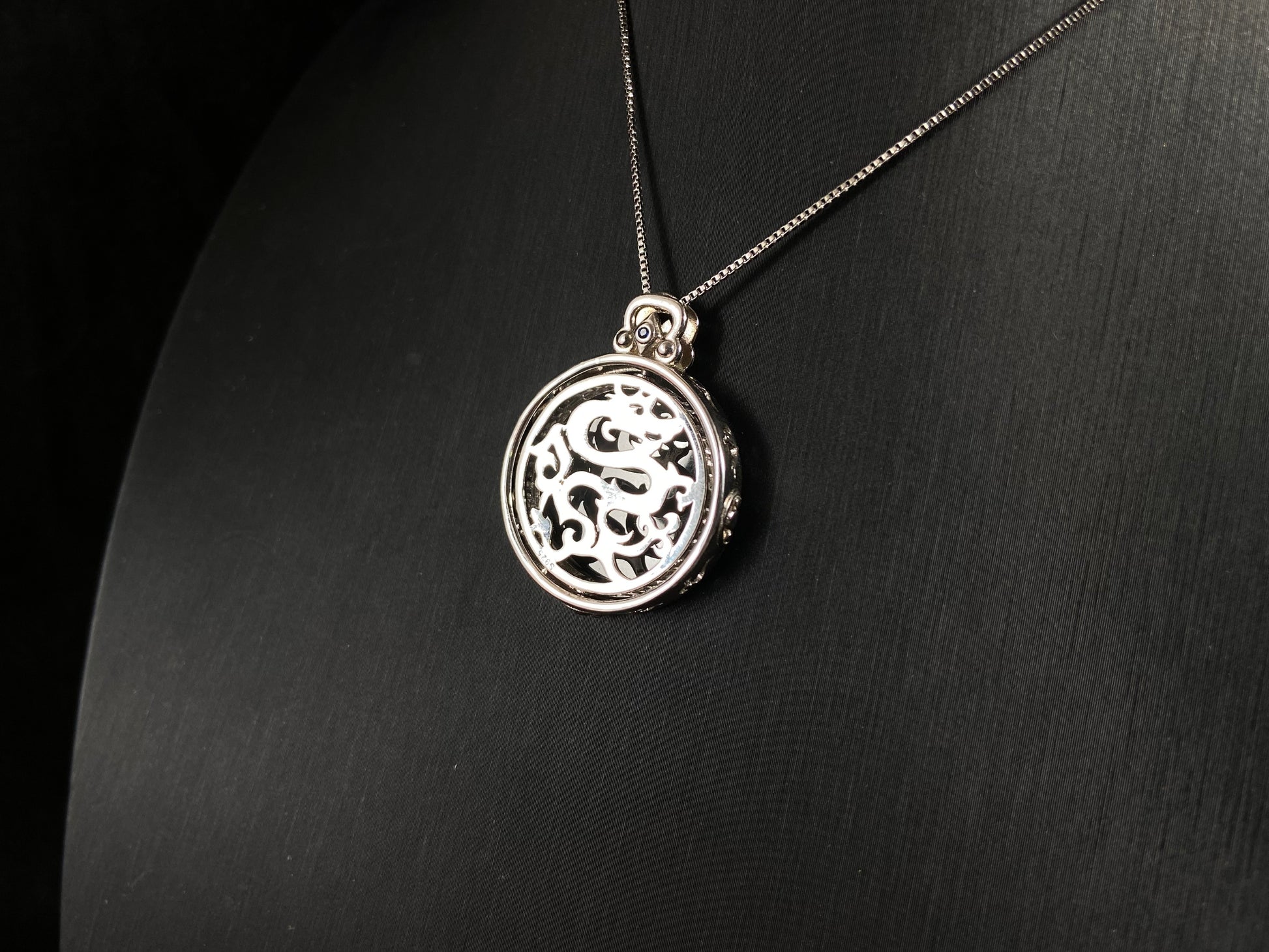 Silver necklace with a round pendant on a dark gray background