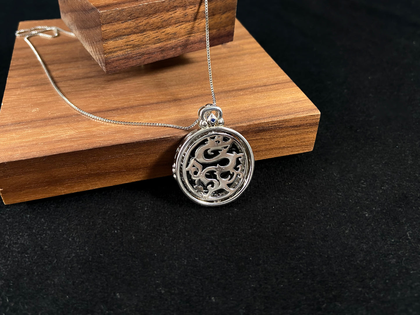 Silver necklace with a round pendant on a dark gray background