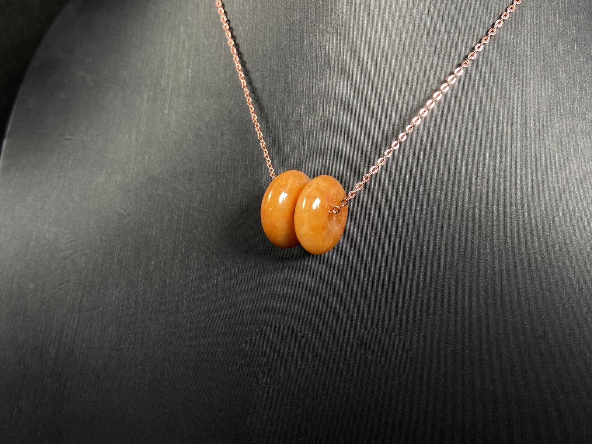 A warm honey hued dual peace buckles jadeite pendant.