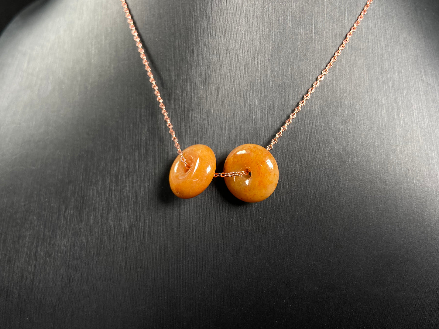 A warm honey hued dual peace buckles jadeite pendant.