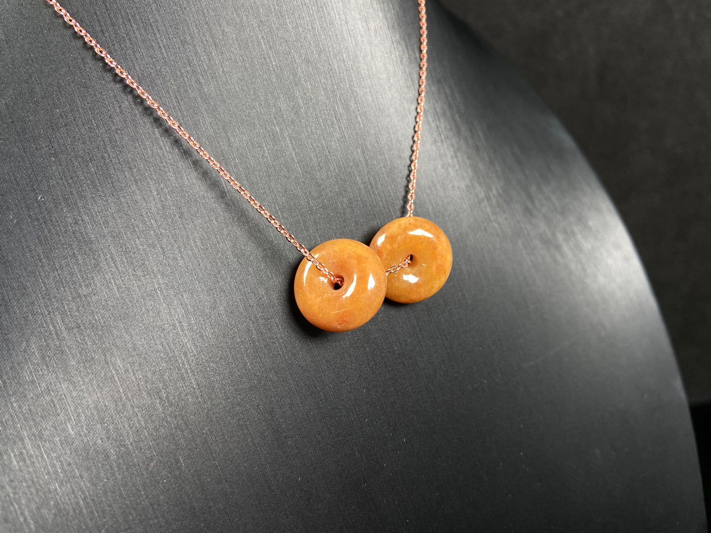 A warm honey hued dual peace buckles jadeite pendant.