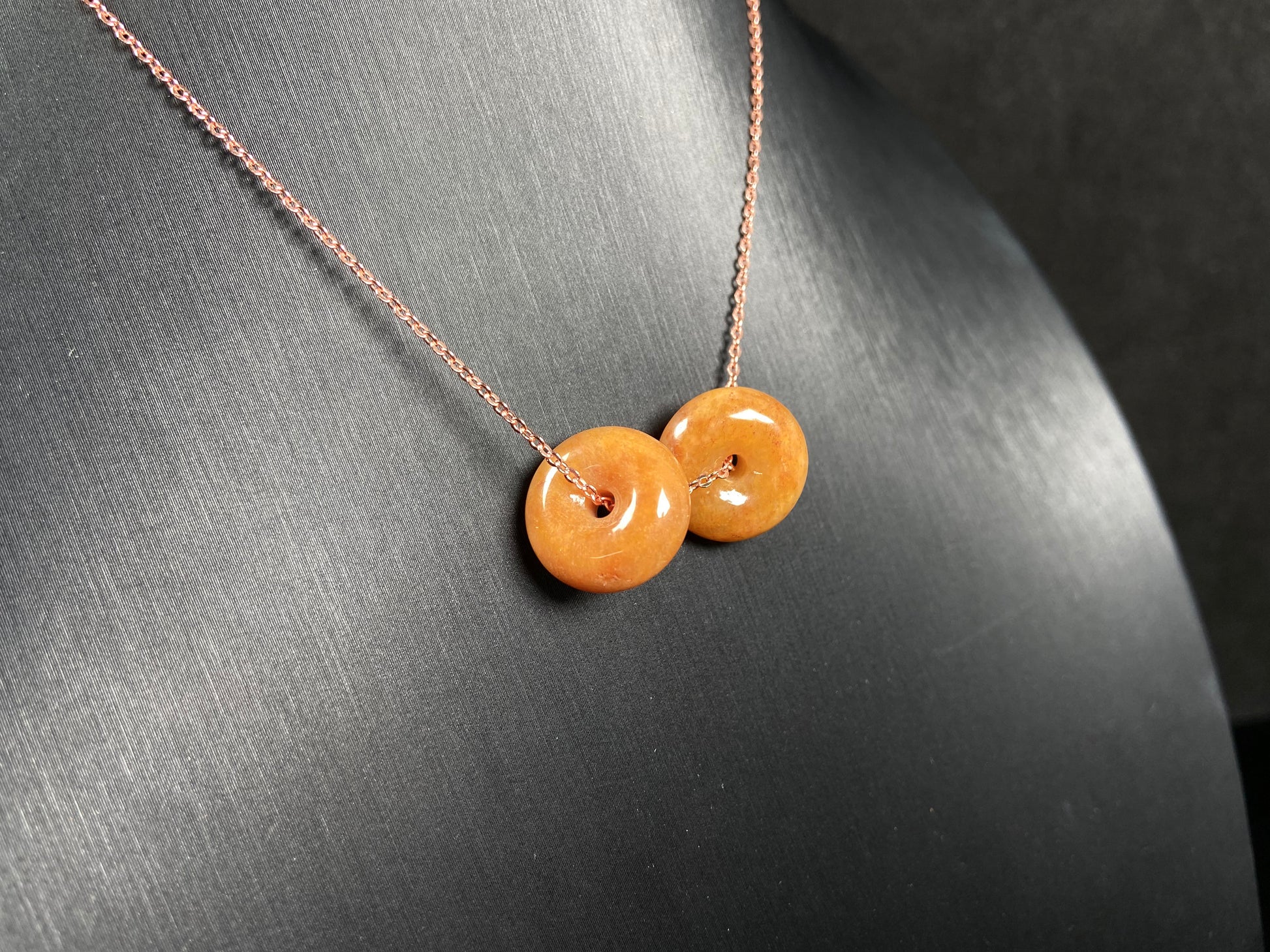 A warm honey hued dual peace buckles jadeite pendant.