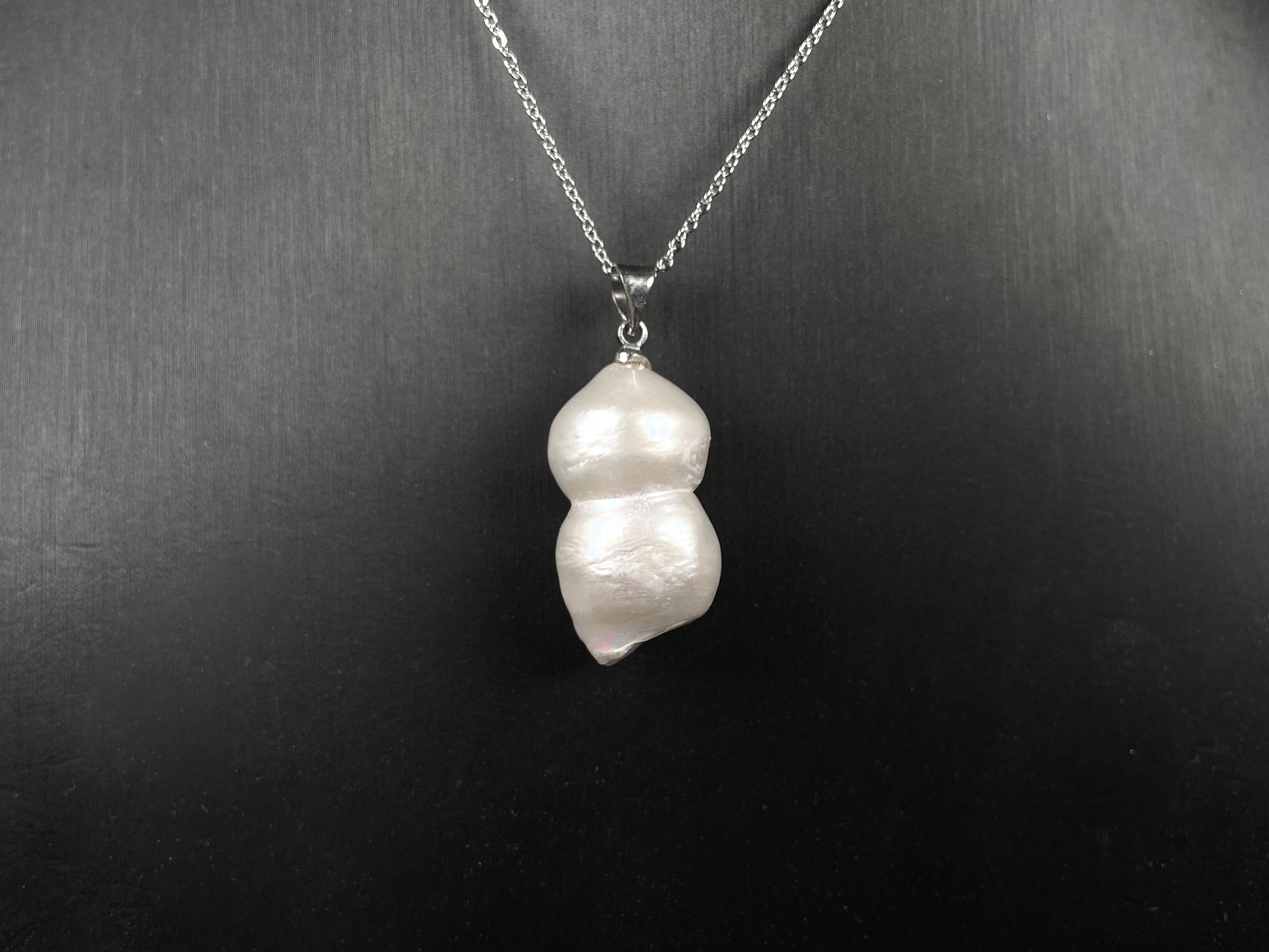 A milky white with blush overtones lucky gourd silhouette pearl pendant.