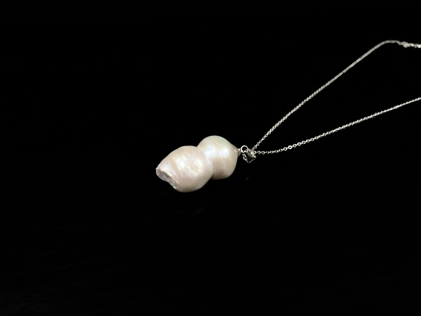 A milky white with blush overtones lucky gourd silhouette pearl pendant.