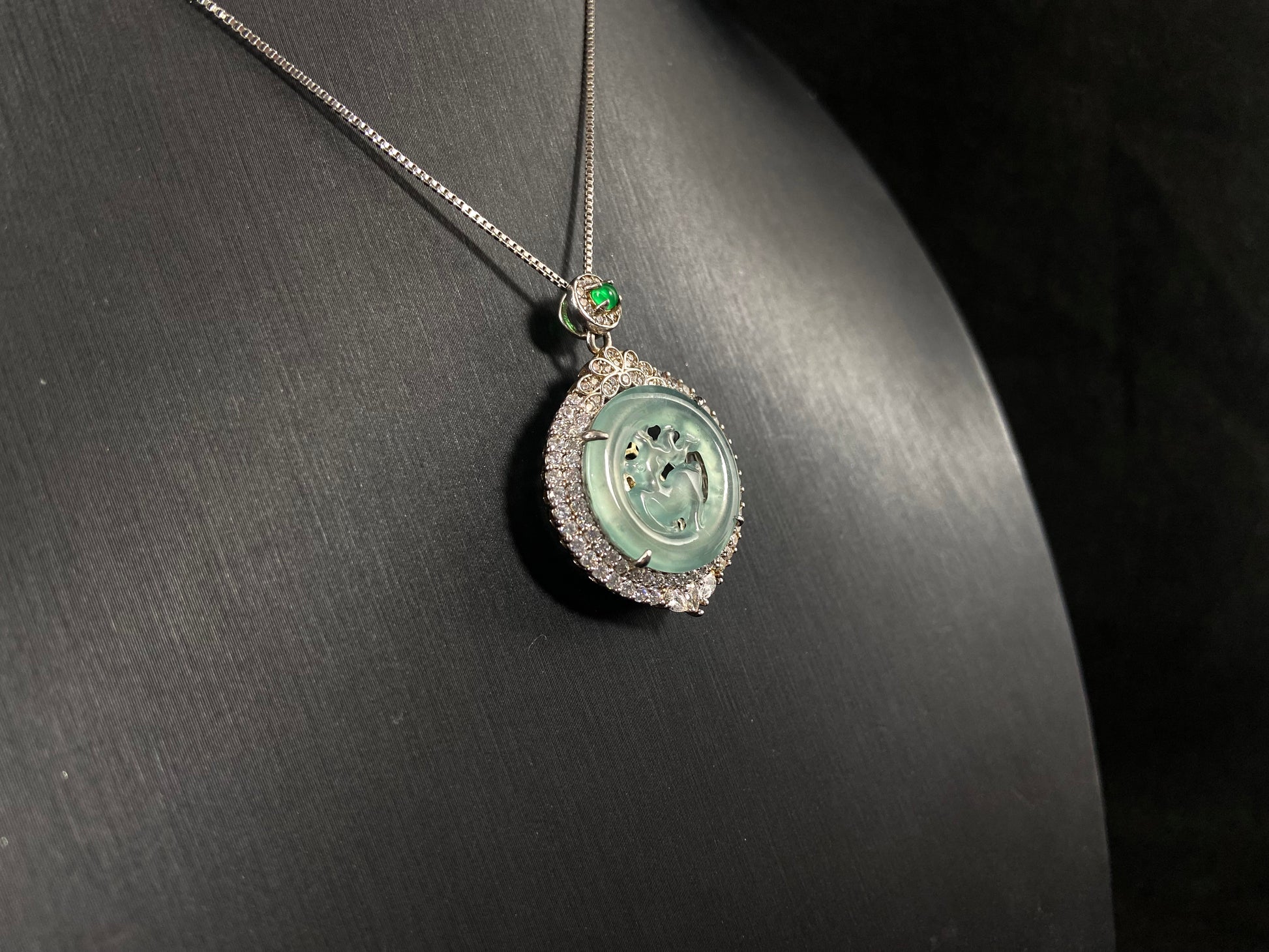A circular pendant features a light green jade deer enclosed within a jade ring, all framed in 925 silver.